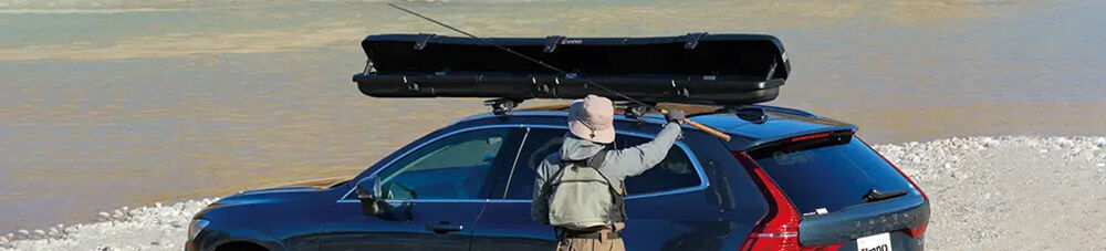 Man grabbing fishing rod out of roof mounting fishing rod cargo box.
