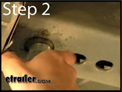 Using a wire brush to scrub a weld nut © etrailer