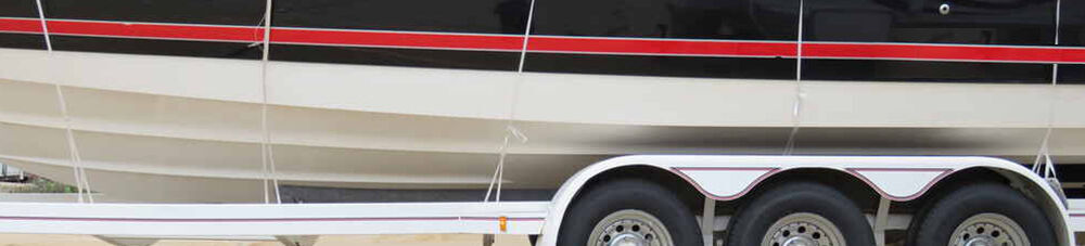 Black and white with red stripe loaded on white boat trailer.