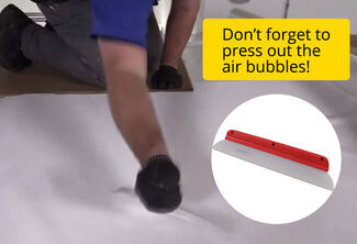 Using a squeegee to press out air bubbles on an RV roof