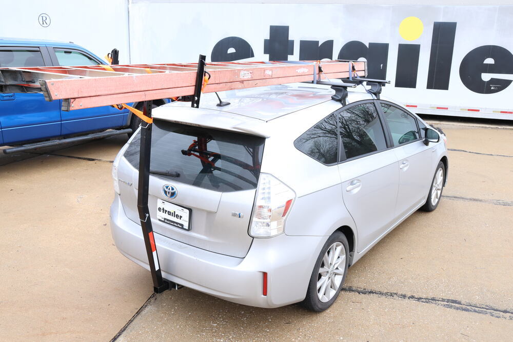 Black Flint Hill Goods truck bed extender with white and red reflective tape hitch mounted on a silver toyota prius