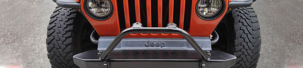 Close up of red Jeep with chrome bumper and grille.