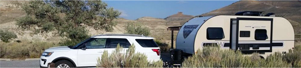 White SUV pulling travel trailer.