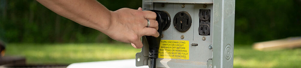 Hand reaching for plugged in RV power cord.