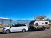 White SUV pulling a travel trailer with mountains in the background.