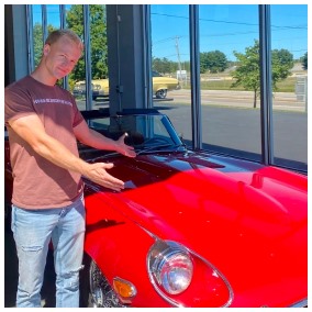 Andrew showing off red sports car.