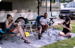 group sitting outside RV. 