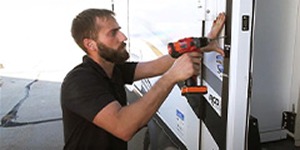 Technician using a power drill to repair the side of an RV.