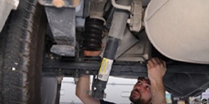 Mechanic working underneath a vehicle to install suspension components.