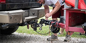 Person connecting a trailer hitch to the back of a pickup truck.