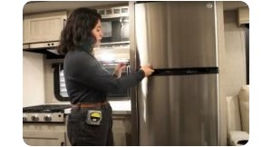 woman opening rv refrigerator door. 