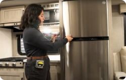 woman opening rv refrigerator door. 
