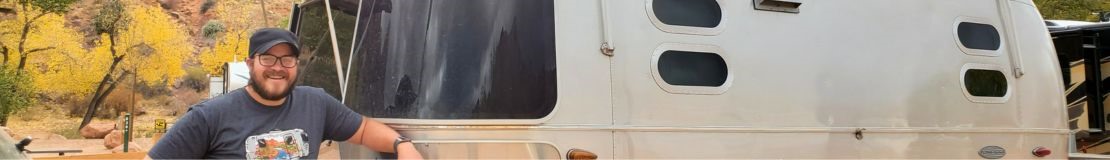 Man standing next to airstream camper. 
