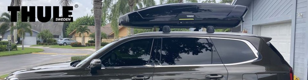 A car with a roof rack, roof box, and bike rack on a dirt road.