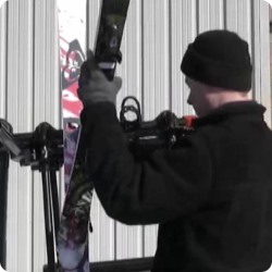 Man putting skis on rack.